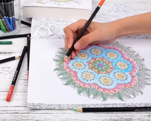 Close-up of hand coloring a mandala with professional oil-based colored pencils