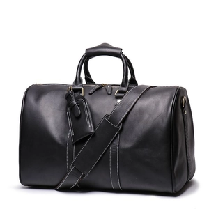 Detail of black leather duffel bag with white contrast stitching and adjustable strap
