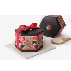 Detail of black hexagonal wedding candy box with red ribbon bow and floral pattern