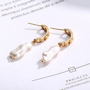 Detailed macro view of baroque pearl earrings with golden chain texture hooks