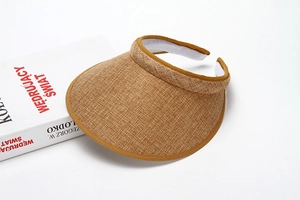 Detail of light brown woven fabric sun visor with dark piping and white sweatband