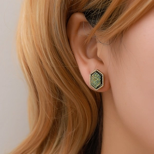 Vintage gold hexagonal stud earrings with sparkling blue-green crystal texture on model