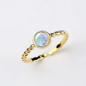 Detailed close-up of a twisted gold ring featuring a round moonstone cabochon setting