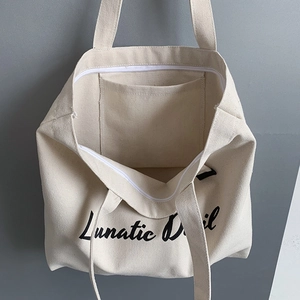 Interior view of canvas tote bag showing spacious main compartment with zipper and pocket