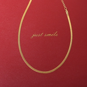 Close-up of golden flat snake bone chain with lobster clasp and extension on red leather
