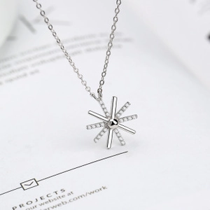 Detail shot of a minimalist starburst pendant necklace with cubic zirconia on white paper