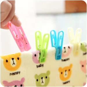 Colorful plastic clothespins for laundry shown drying a cartoon bear towel