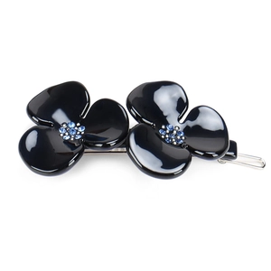 Detail of floral hair clip with black three-petal flowers and blue crystal centers