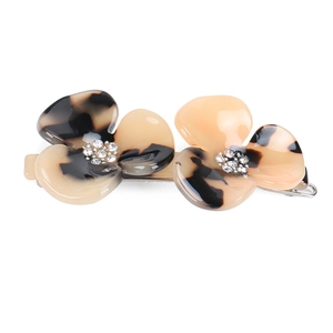 Close-up of dual acetate flower hair clip with amber texture and rhinestone center