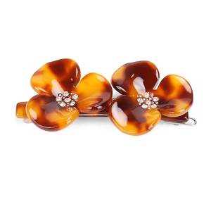 Detailed view of tortoiseshell floral hair clip with white rhinestones on silver metal