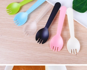 Detail view of colorful disposable plastic forks and spoons arranged on a wooden surface