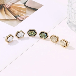 Macro detail of hexagonal glitter earrings in silver, peacock green and champagne gold