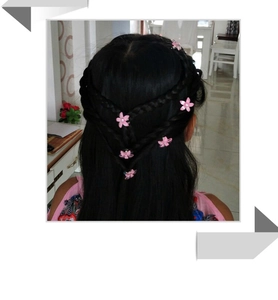 Détail de pinces à cheveux fleurs roses en strass pour décorer les tresses des filles