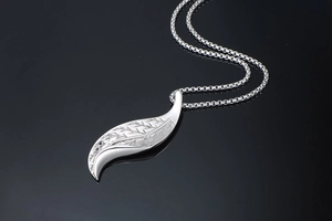 Macro shot of silver leaf pendant with detailed textures on a sturdy box chain