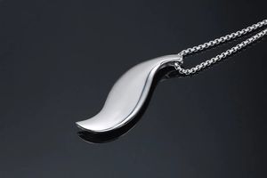 Detailed view of a silver leaf pendant on a box chain over a black reflective surface