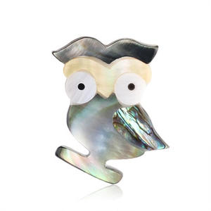 Macro detail of owl brooch crafted with iridescent abalone shell inlay on white background