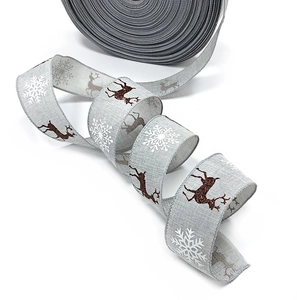 Close-up of burlap Christmas ribbon with white snowflake and glittery elk patterns