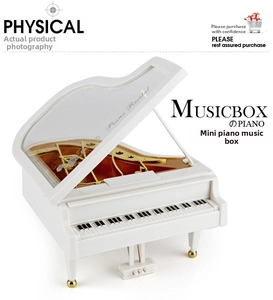 Macro detail of a small white piano music box showing the golden mechanical movement inside