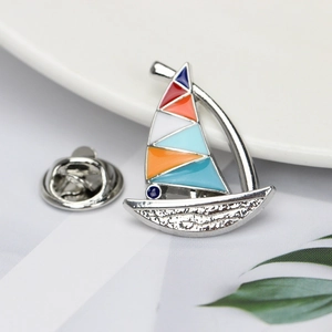 Macro shot of colorful enamel sailboat brooch with polished silver metal finish