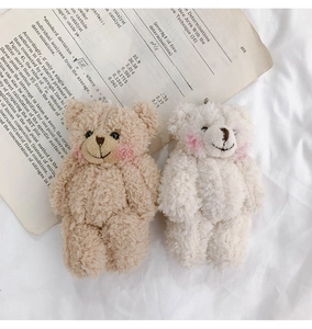 Close-up of cute beige and white plush teddy bear charms on academic paper background