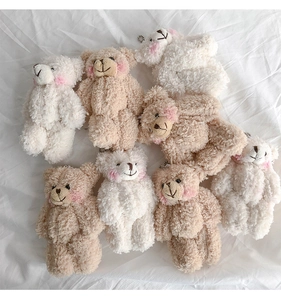 Close-up of cute white and beige plush bear keychains with metal ball chains