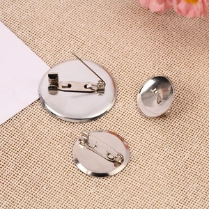 Silver nickel-tone round brooch base tray settings in multiple sizes on woven mat