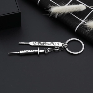 Silver metal syringe and thermometer charms keychain on a decorative black background