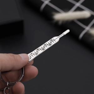 Close-up of silver thermometer keychain pendant showing precise engraved scale numbers