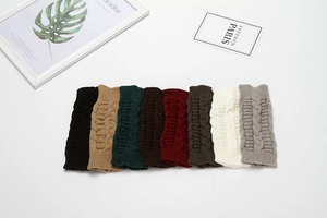 Flat lay of eight colorful knit fingerless gloves with cable knit patterns on white background