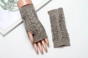 Detail of grey cable knit fingerless gloves with a textured pattern on white background