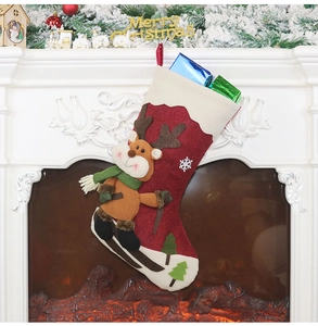 Detail eines roten Weihnachtsstrumpfs aus Stoff mit 3D-Rentier an einem gemütlichen Kamin