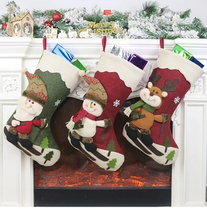 Drei 3D-Weihnachtssocken mit Weihnachtsmann, Schneemann und Rentier am Kamin aufgehängt