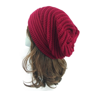 Detail shot of wine red knitted beanie showing thick textured weave and slouchy style