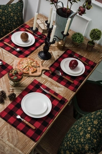 Detailed top view of four red and black checkered placemats on a rustic wooden table