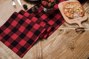 Detail of red and black buffalo plaid table runner on wood table for Christmas decor