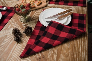Close-up of red and black plaid cotton linen placemat on a festive rustic wooden table