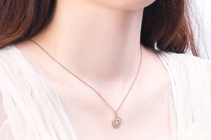 Model wearing a rose gold halo pendant necklace with a large center diamond and tiny gems