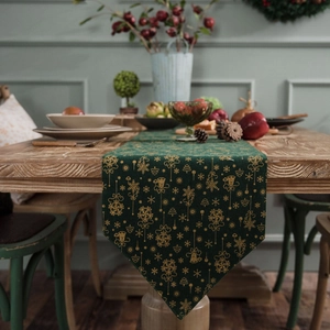 Dark green Christmas table runner with gold snowflake patterns on a rustic wooden table