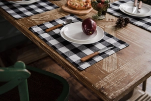 Detail of red and black checkered cotton linen placemat with white ceramic tableware