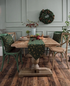 Close-up of green Christmas table runner with gold snowflake patterns on a wooden table
