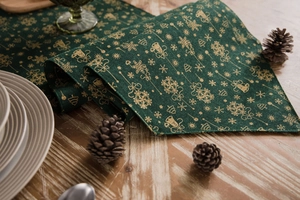 Detail of green Christmas table runner with golden snowflakes on a wooden table