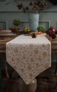 Detailed close-up of festive Christmas table runner with golden snowflake and bell patterns