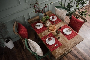 Close-up of red and gold festive placemats on a wooden table for holiday dining