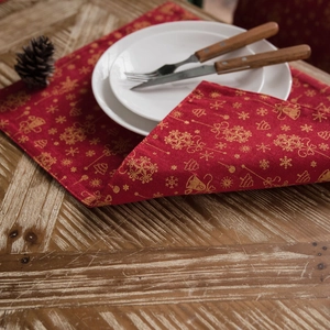 Red festive Christmas placemat with gold snowflake patterns on a rustic wooden table