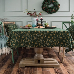 Dark green Christmas tablecloth with golden snowflake prints in a festive dining setting