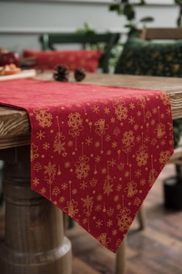 Detail of red Christmas table runner with golden snowflakes on a rustic wooden table