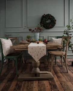 Detail of beige Christmas table runner with gold snowflake foil print and matching cushions