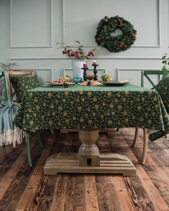 Detailed close-up of dark green Christmas tablecloth with gold festive patterns and textures