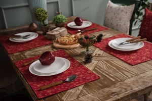 Set of four red festive placemats with gold holiday patterns and white plates