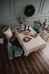 Detail of floral cotton linen tablecloth and matching cushion covers in rustic dining setting